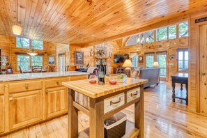 Interior de una cabaña de madera con cocina, comedor y sala de estar.