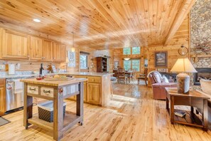 Interior espacioso de una cabaña de madera con cocina, comedor y sala de estar.