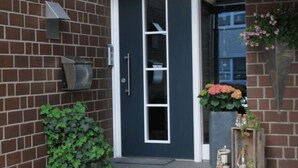 A brick building with a dark blue door, a small garden area with plants, and a number '52' on the wall. - Holiday Apartment Langkamp (Neuenkirchen)