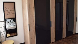 A room with a bed, a small stool, and a wardrobe with a mirror. - Holiday Apartment Langkamp (Neuenkirchen)