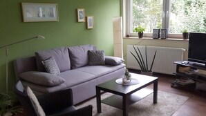 A modern living room with a grey sofa, a coffee table, a black armchair, and a television. - Holiday Apartment Langkamp (Neuenkirchen)