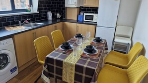 Une cuisine compacte comprenant un coin repas, un lave-linge et un four à micro-ondes.