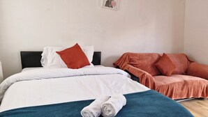 Un lit bien fait, avec une literie blanche et turquoise, un plaid turquoise et une serviette blanche enroulée.