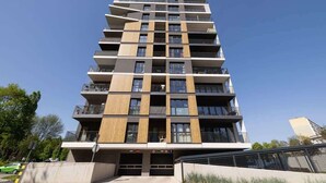 Un immeuble résidentiel à plusieurs étages, doté de balcons, d’une entrée de garage et surplombant un ciel dégagé.