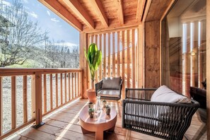 A wooden deck with a round table, two wicker chairs, and a potted plant. - Colibri - Cozy Apartment in Les Gets (Les Gets)