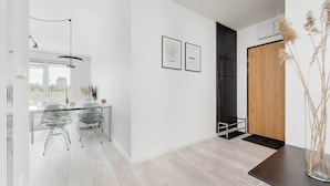 A modern interior with a dining area, a black vertical partition, and a wooden door.