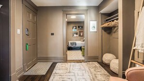 A hallway leading to a bedroom with a bed, a closet, and a door with a lock.