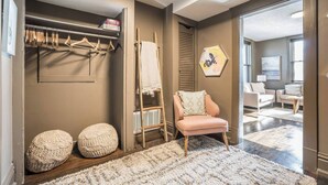A modern interior with a closet, a pink chair, and a view into another room.