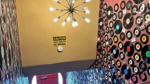 A staircase with a wall covered in vinyl records, a caution sign, and a handrail.