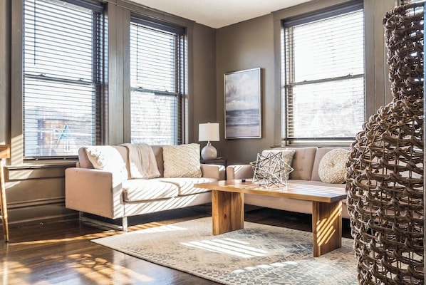 A modern living room with a sofa, coffee table, and a decorative wall piece.