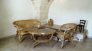 Ein Zimmer mit Steinbogen-Decke, Korbmöbeln und Fliesenboden.