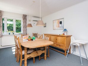 A dining area with a wooden table, chairs, a cabinet, and a white chair. - 6 Person Holiday Home in Hojer (Højer)