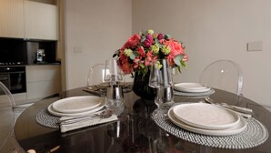 Een eettafel gedekt met borden, bestek en een vaas met bloemen.