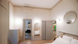 Een moderne hotelkamer met een groot bed, een kledingkast, een spiegel en een badkamer zichtbaar door een open deur.
