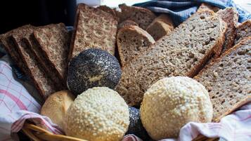 Een mand met diverse broden, waaronder volkoren, roggebrood en brood met papzaad.