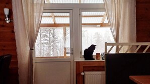 A room with a wooden interior, a window with curtains, a radiator, a chair, and a table. - Gopshusgården - Rum och Stugor (Mora)