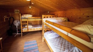 A cabin with three bunk beds, a fan, a small shelf with a picture, and a wooden floor. - Gopshusgården - Rum och Stugor (Mora)
