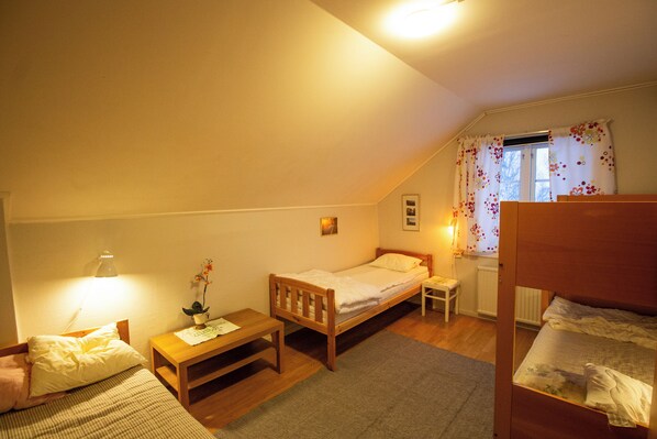 A small, cozy bedroom with a single bed, a bedside table, a lamp, and a window with curtains. - Gopshusgården - Rum och Stugor (Mora)