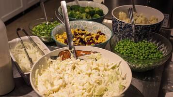 Una encimera de cocina con varios recipientes que contienen diferentes alimentos como verduras y maíz.