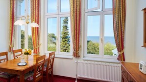 A dining area with a table, chairs, and a view of the sea through large windows. - Strandvillen Wald & See (Zinnowitz)
