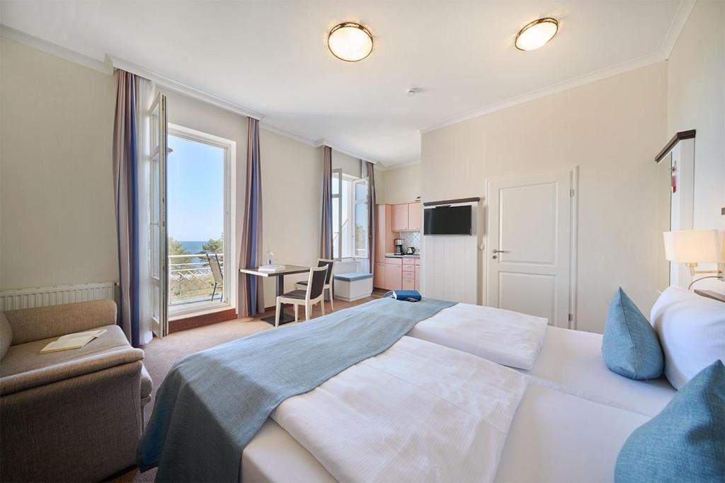 Habitación de hotel con dos camas, un escritorio, una silla, un televisor y vista al mar.