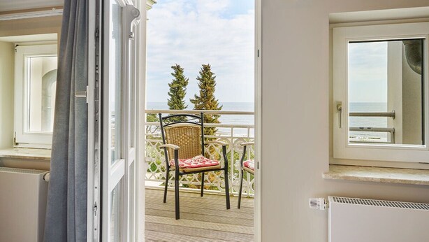 A balcony with wicker chairs, a view of the sea, and a white railing. - Strandvillen Wald & See (Zinnowitz)