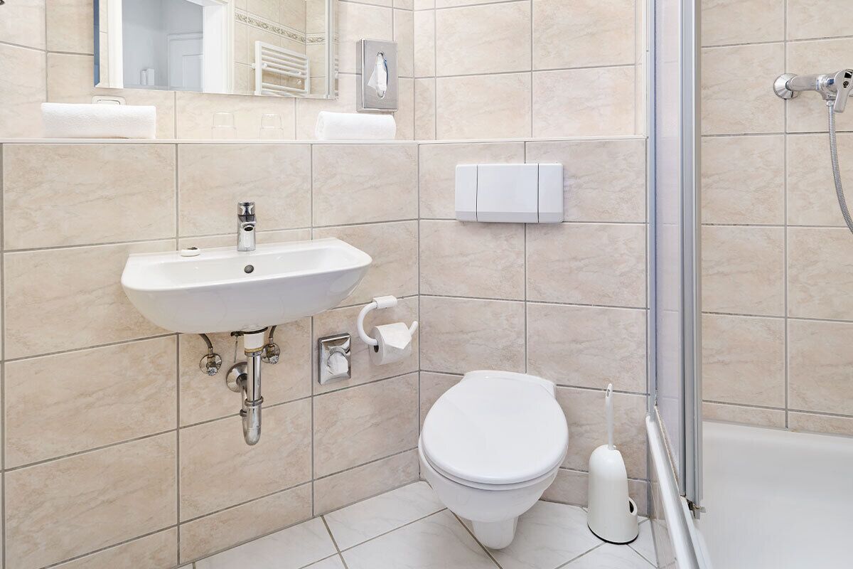 Un baño moderno con lavamanos, inodoro y ducha.