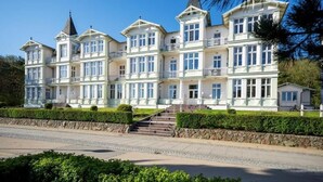 A large, multi-story building with a symmetrical facade, multiple balconies, and a prominent tower. - Strandvillen Wald & See (Zinnowitz)