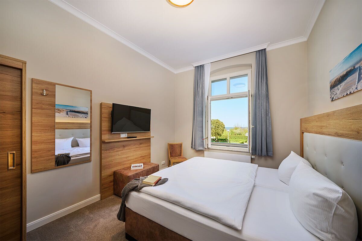 Une chambre d’hôtel avec un lit, une télévision, une fenêtre avec des rideaux et une vue sur l’extérieur.