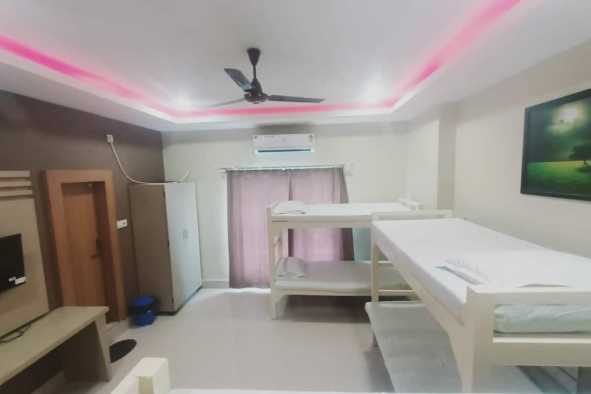 Habitación de hotel con literas, ventilador de techo, aire acondicionado, televisor y un cuadro en la pared.