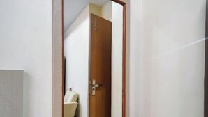 Ein Badezimmer mit Spiegel, Holztür und weißer Wand.