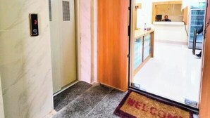 Ein Hotel Eingang mit Marmorwand, Holztür und Fußmatte.