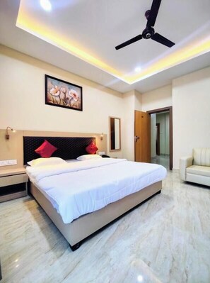 A bedroom with a bed, a ceiling fan, a painting, a nightstand, a mirror, and a door.