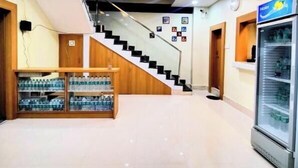 Eine Hotte lobby mit Treppe, Deckenventilator, Wasserspender und Kühlschrank.