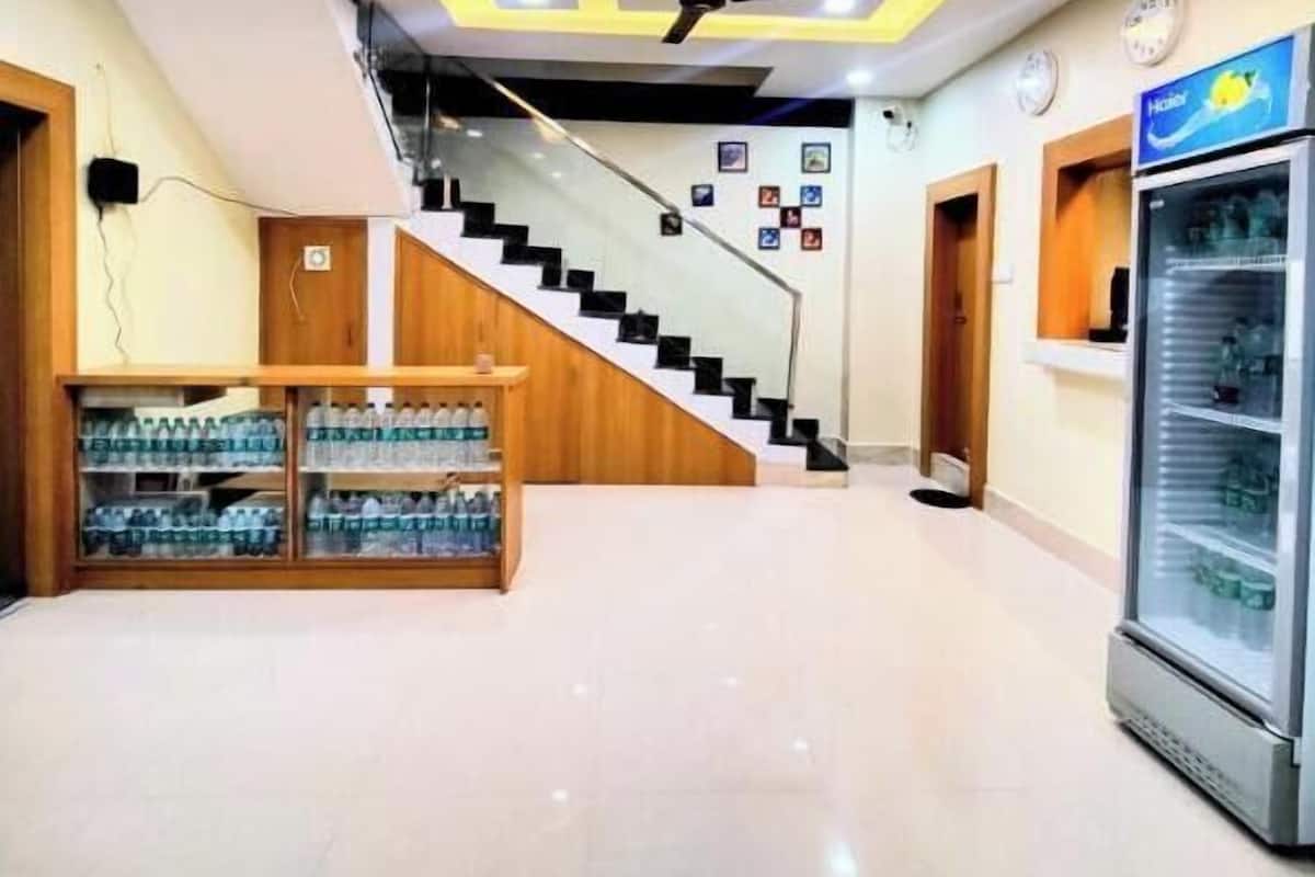 Un vestíbulo de hotel con una escalera, un ventilador de techo, un dispensador de agua y un refrigerador.