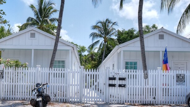 A white building with a white picket fence, numbered 709, and a motorcycle parked in front. - Beautiful, private,  bright one bedroom cottage walk to Duval, Truman Waterfront, Santiago's Bodega (Key West)