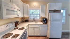 A kitchen with white cabinets, a microwave, stove, sink, and a refrigerator. - Beautiful, private,  bright one bedroom cottage walk to Duval, Truman Waterfront, Santiago's Bodega (Key West)