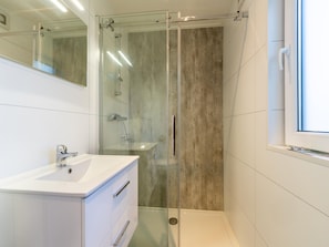 A modern bathroom with a glass-enclosed shower, a white sink, and a large mirror.