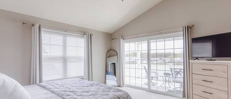 Un dormitorio con cama, cómoda, ventilador de techo y ventanas amplias.