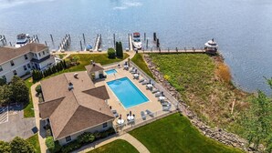 An aerial view of a residential area with a swimming pool, lounge chairs, and a dock with boats. - On The River, Assn Pool & Hot Tub, Water Taxi in Summer (St. Joseph)