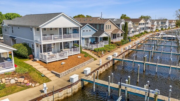 A waterfront residential area with houses featuring balconies and a dock extending into the water. - On The River, Assn Pool & Hot Tub, Water Taxi in Summer (St. Joseph)
