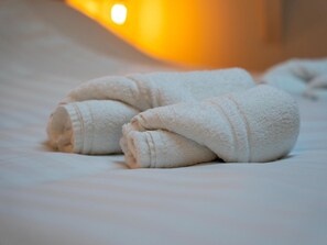 A neatly folded white towel on a bed.
