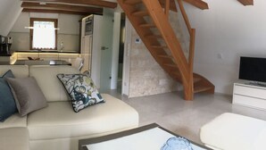 Een modern loftappartement met een woonkamer, keuken en een houten trap.
