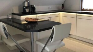 Een moderne keuken met een zwart aanrecht, witte kastjes en een hangende lamp.