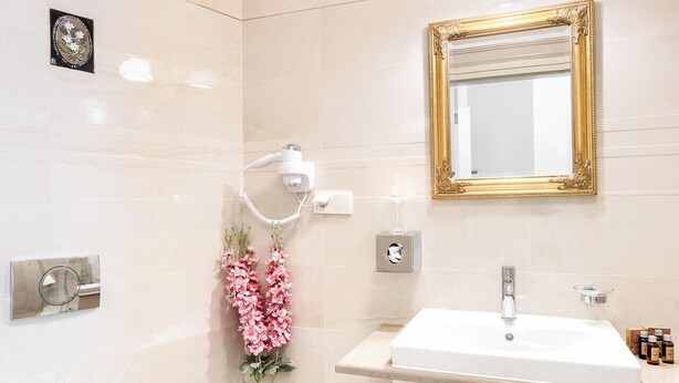 A modern bathroom with a white toilet, a sink with a gold faucet, and a vanity with drawers.