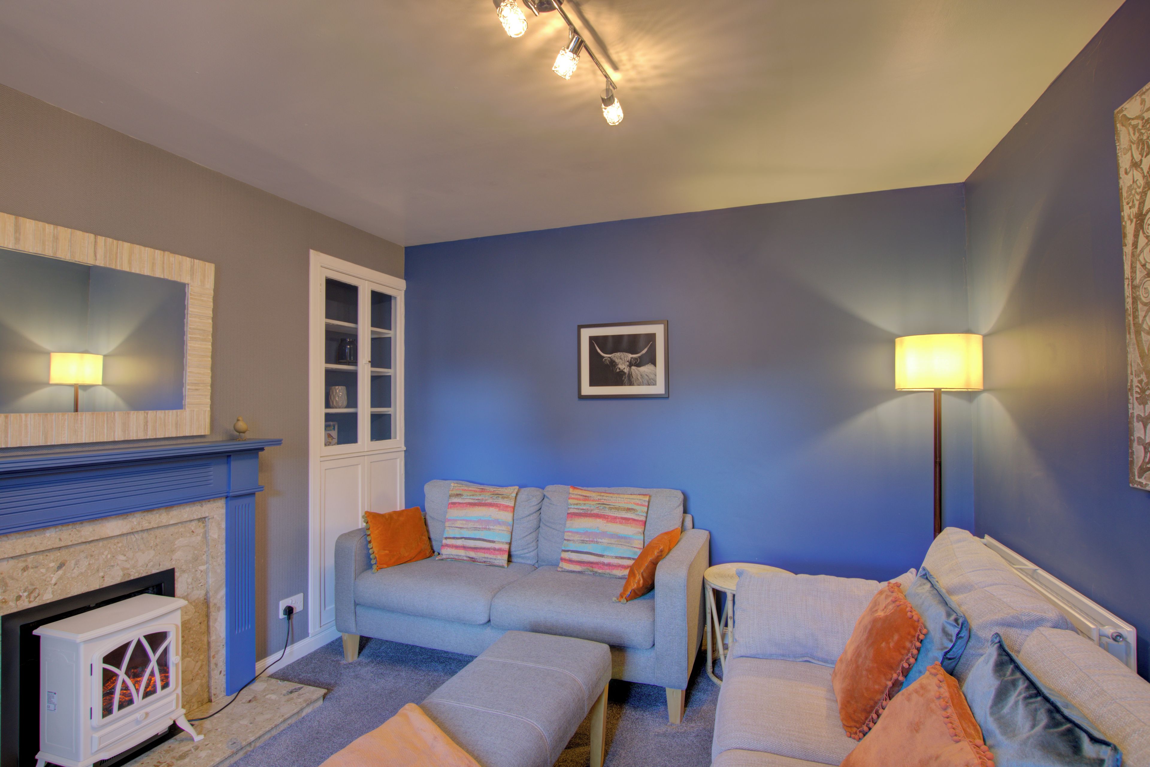 A living room with a fireplace, a sofa set, and a blue wall.