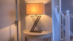 A corner lamp with a rectangular shade on a white table against a wall. - A 2-bedroom cosy cottage based at the heart of the rural village of Brora. (Brora)