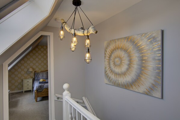 A staircase with a white railing, a wall-mounted light fixture, and a large abstract painting.