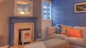 A living room with a fireplace, a sofa, and a window. - A 2-bedroom cosy cottage based at the heart of the rural village of Brora. (Brora)