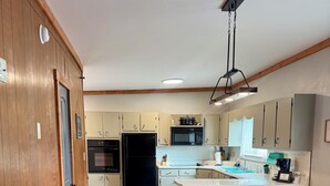 A kitchen with wooden cabinets, a black refrigerator, a microwave, and a sink.